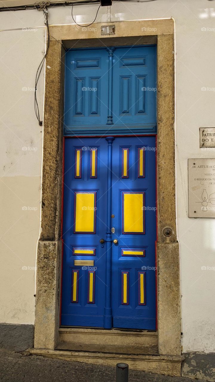a massive yellow and blue door with rectangular inlay and marble casing