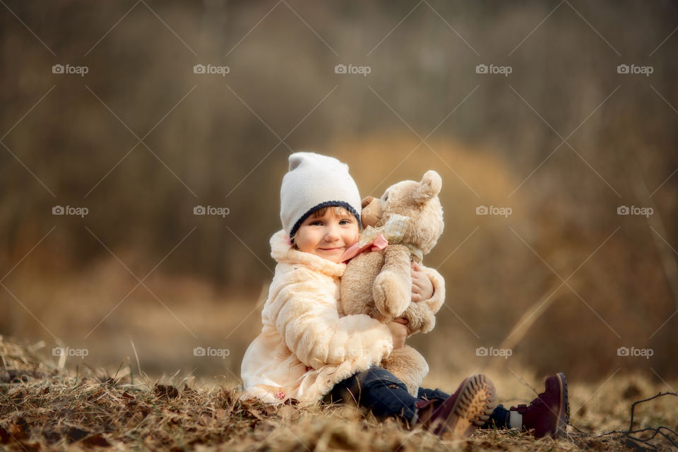 Little girl with teddy bear in spring park