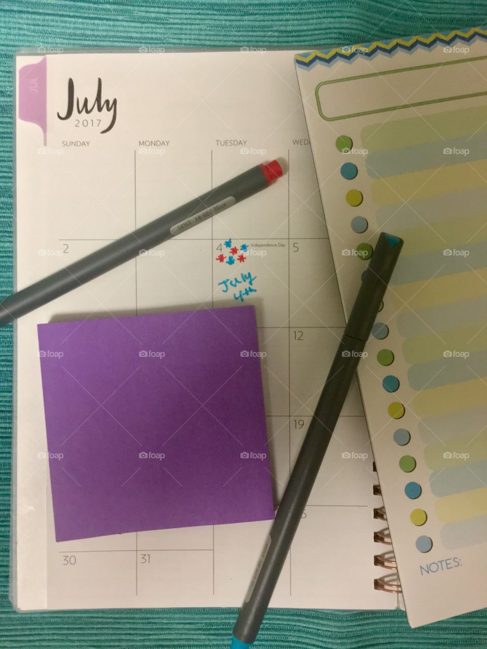 Monthly planner and to-do list with pens and sticky notes 