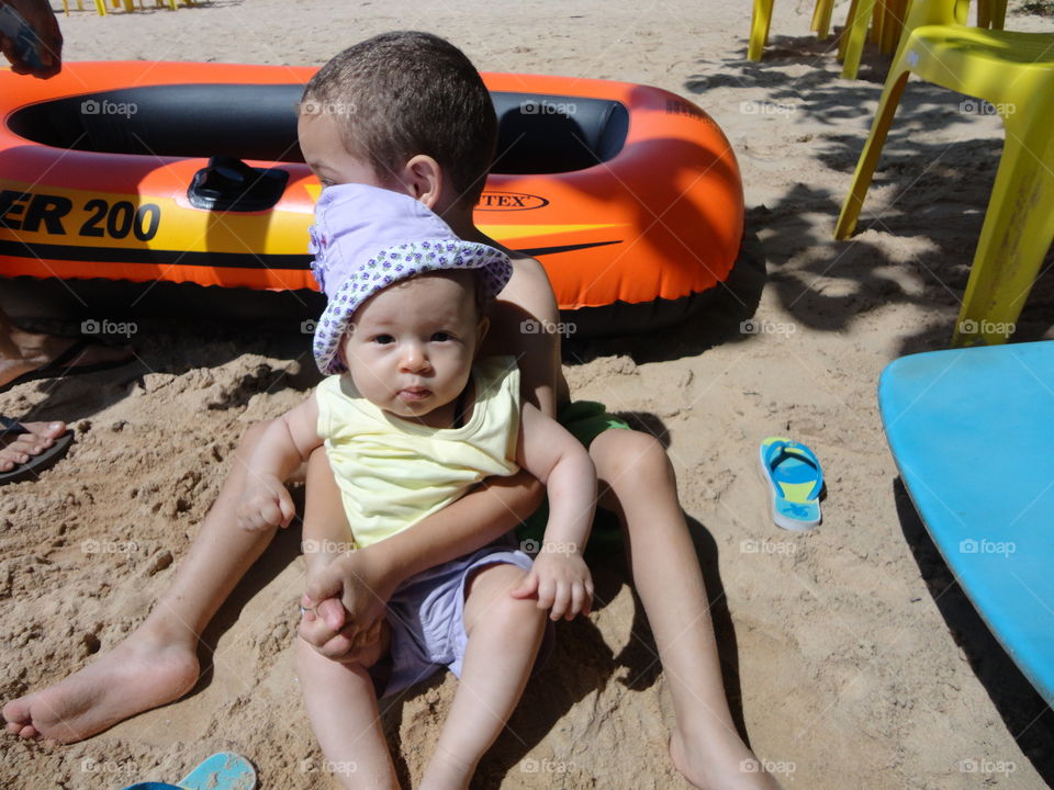 Sibling sitting on sand at beach