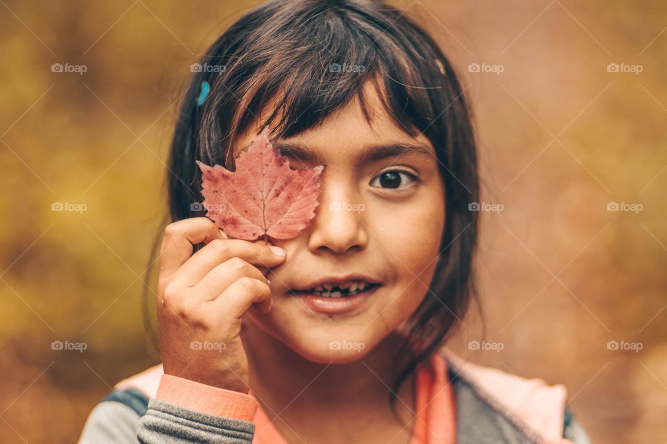 Cute little girl with a leaf close to her face