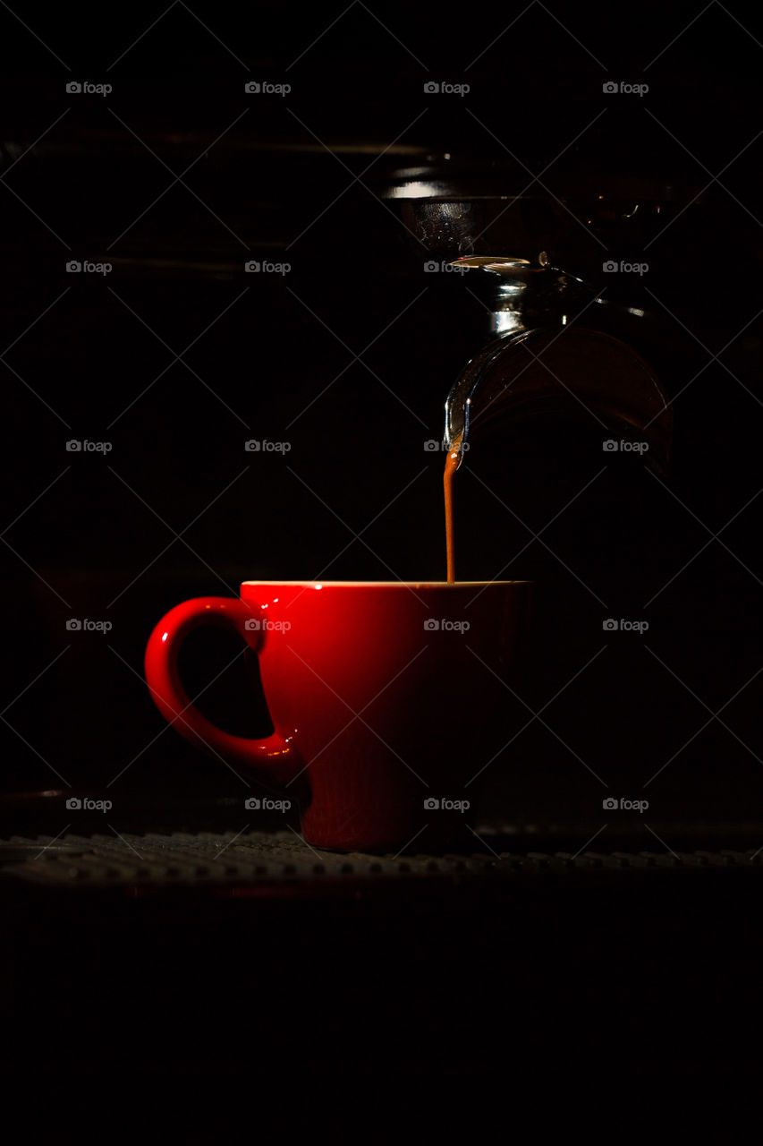 Coffee espresso pouring into a red cup