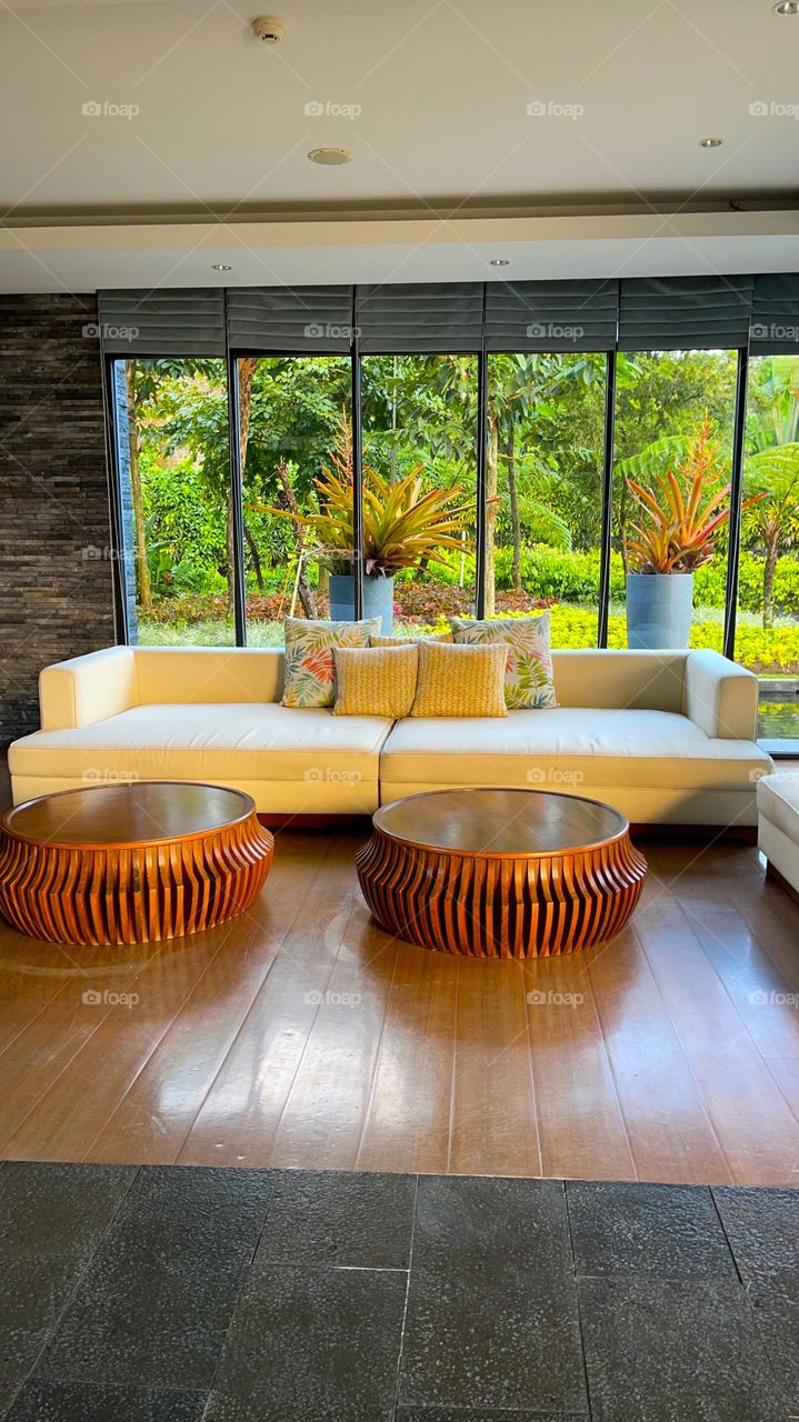 Guest room interior design with a garden background and nice tables and white sofa, with wooden tiles looks beautiful