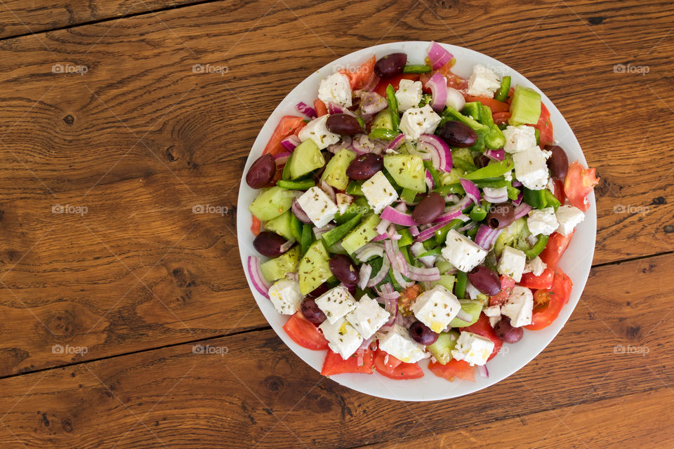a top view of a homemade Greek salad.  the main ingredients are tomatoes, cucumber, green pepper, feta cheese and kalamata olives.