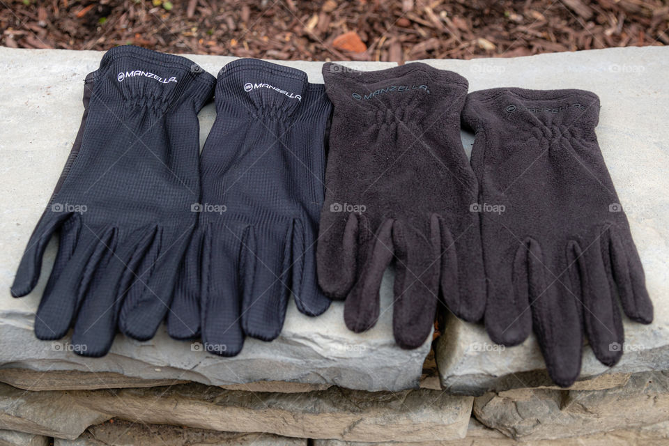 Manzella black touchtip gloves. Multiple pairs of product isolated - shot outdoors on a firepit in the woods. 