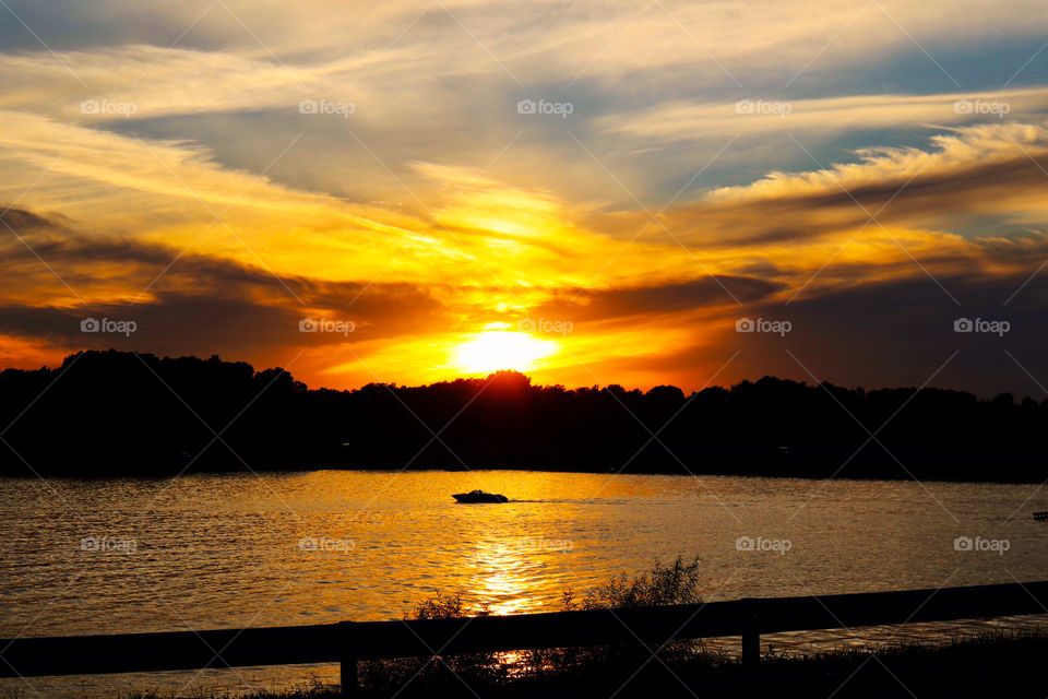 A beautiful sunset on the lake in Indiana on a warm summer day with a boat in the water 