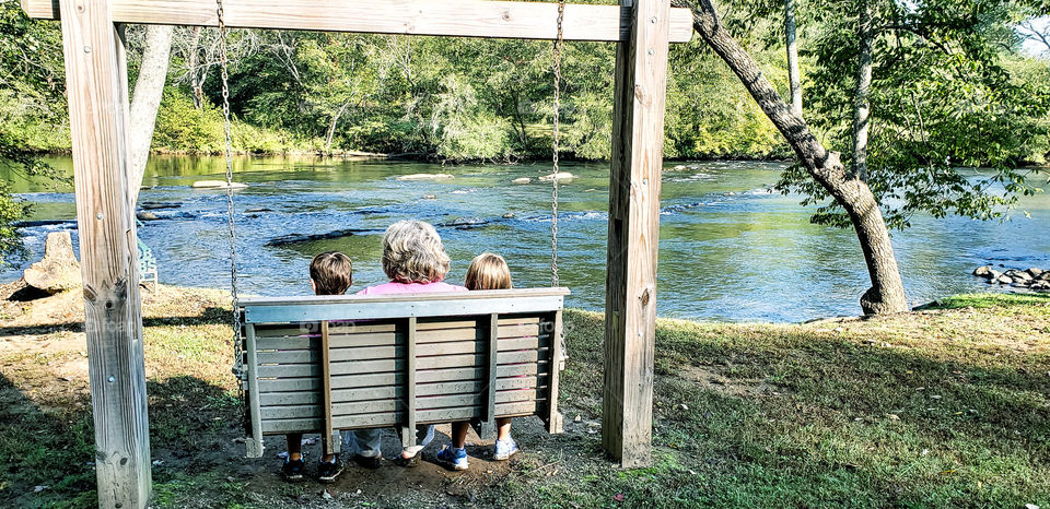 Grandma and kids sitting in a swing.