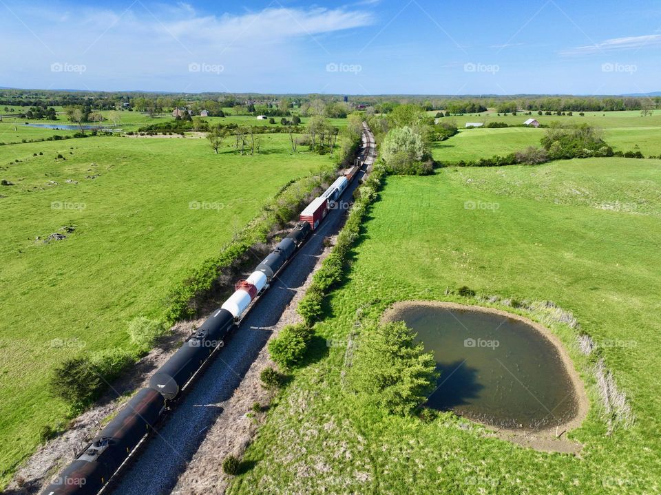 Flying above rural Virginia a train passes by on a sunny spring day 