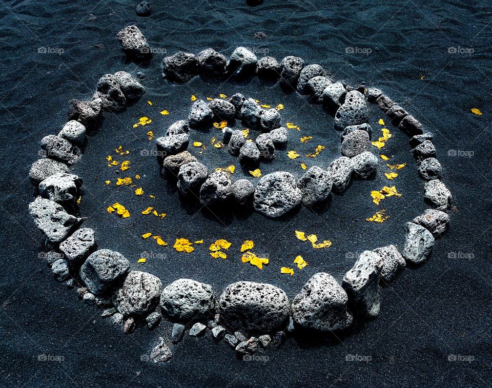 Stone spiral in the sand adorned with leaves
