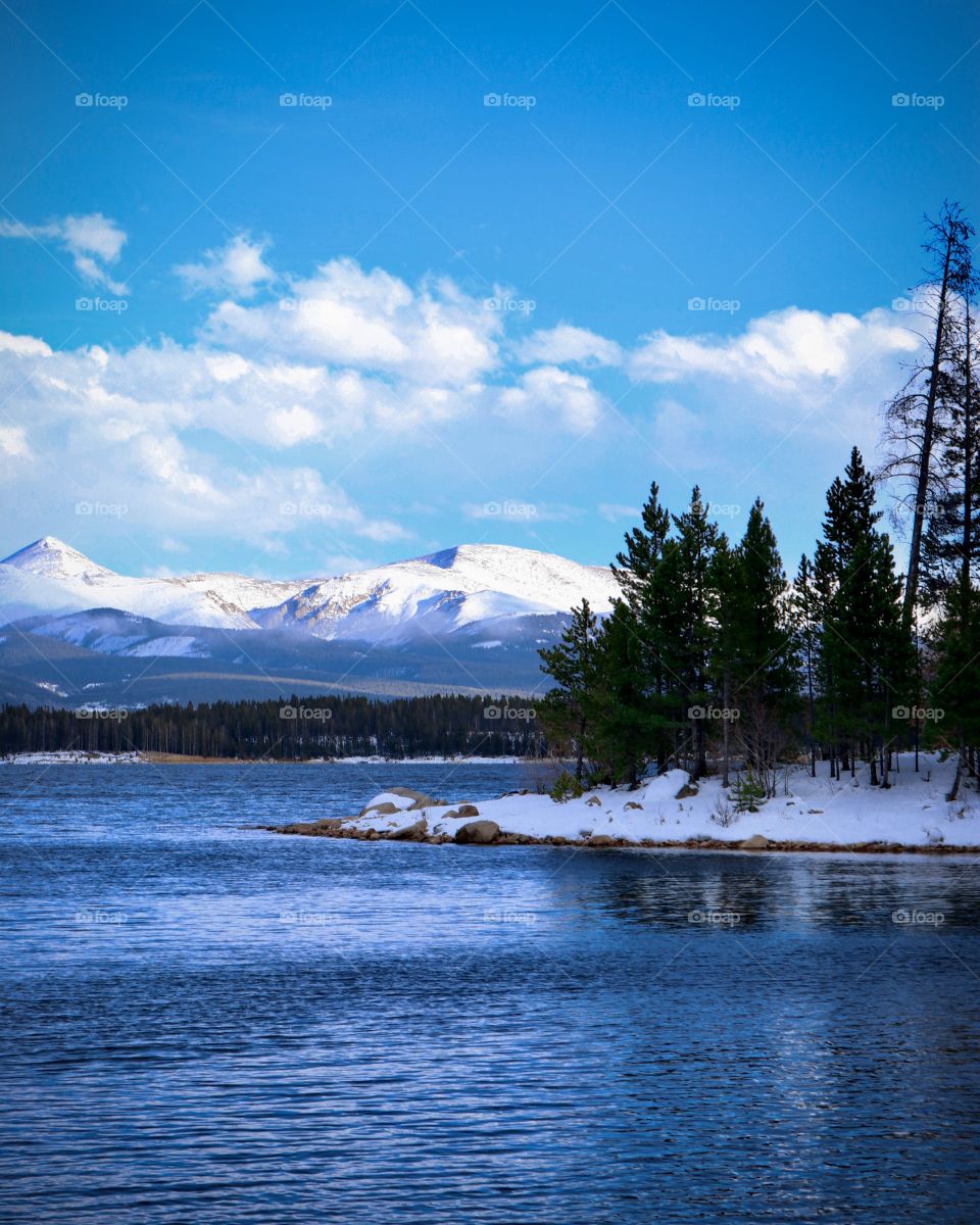 Views in the mountains across the lake. A clear blue sky above the snow covered mountains.