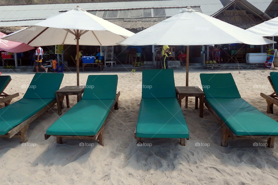 green beach chairs and white umbrellas