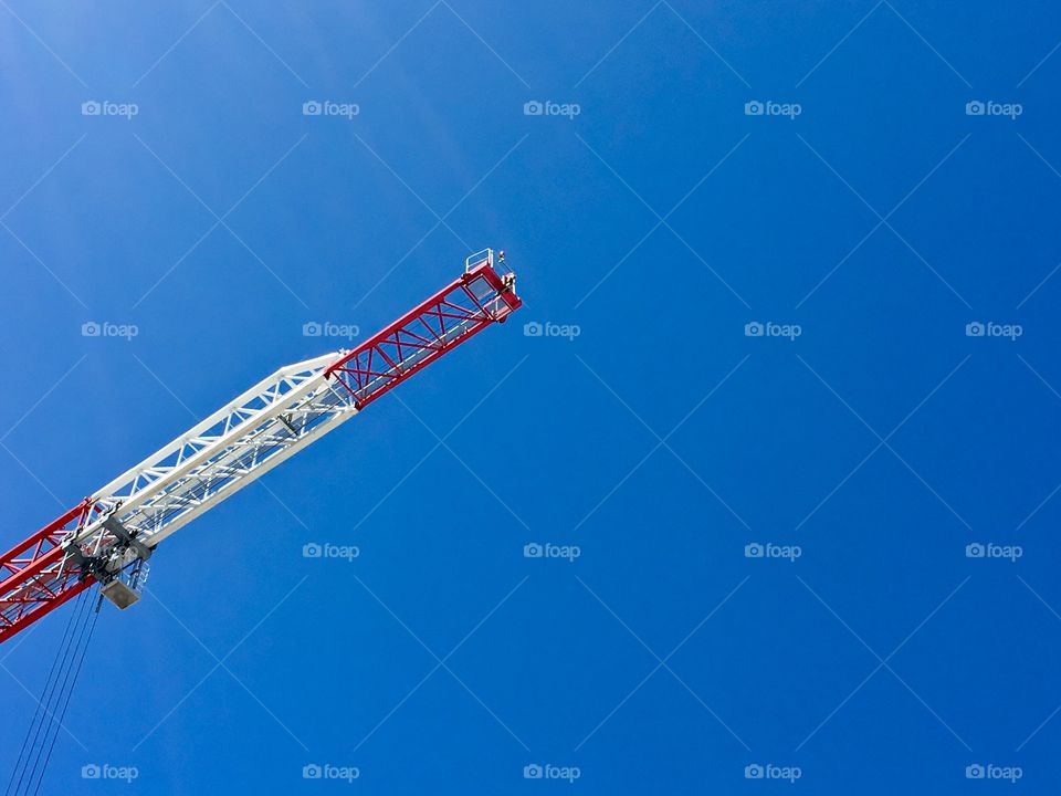 Construction crane high in the sky against a clear blue sky