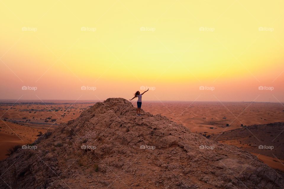 Girl silhouette at desert hill during sunset 