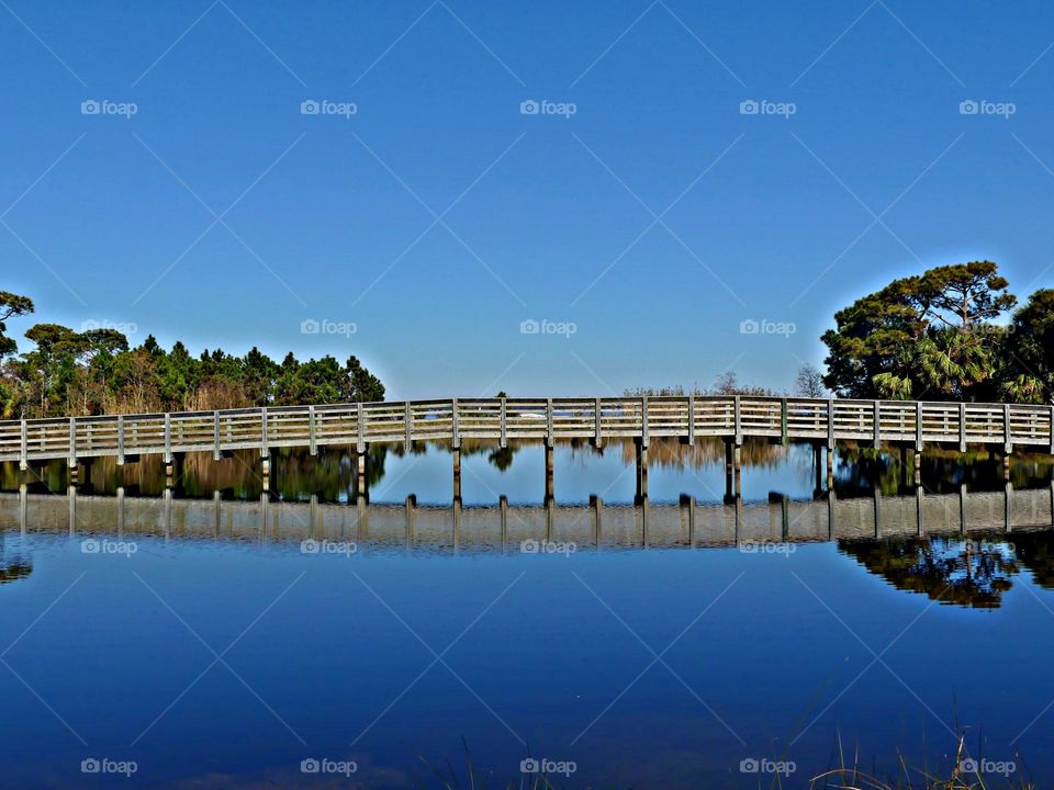 Seeing double - Bridge reflection over waterway from bay to Gulf of Mexico. Blue sky and landscape in background