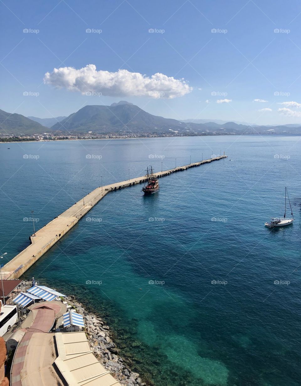 Горы устремляются к небу, омываемые лазурными волнами моря. Небо сияет яркими оттенками, создавая неповторимую красоту природы.