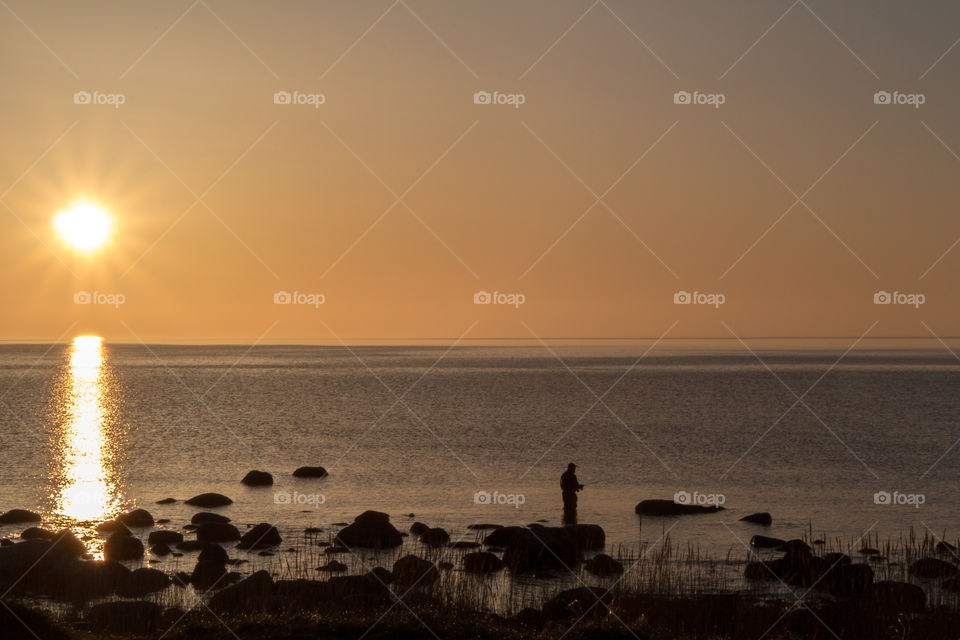 Morning fishing . A man is fishing at Kivik, Sweden during sunrise.