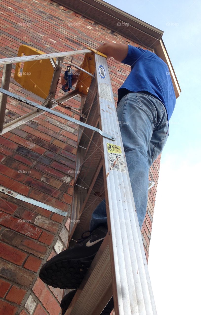 My home repair man. Husband repairing mortar on top of a ladder