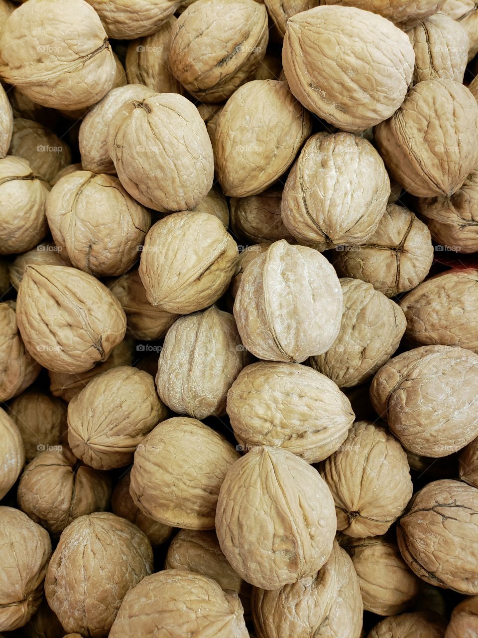 Closeup of details and texture of a pile of  walnuts in their shells at the local market