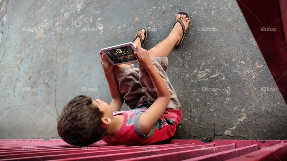 Tranquilamente menino no chão com jogos online.