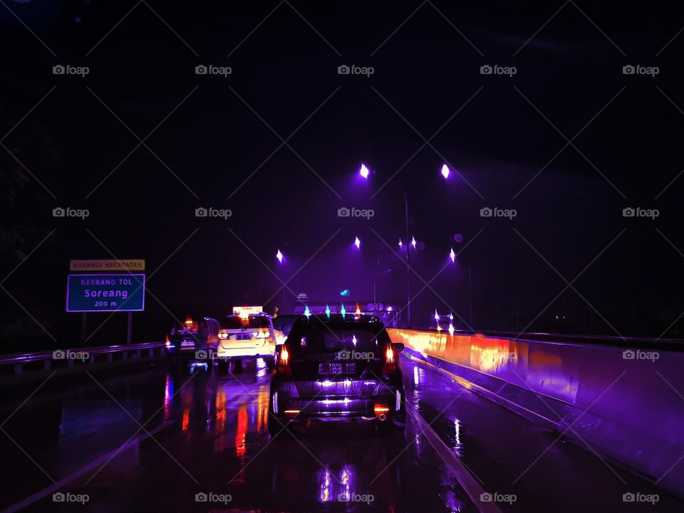 Night view of toll gate, heavy rain, road surface reflecting light, street lighting shimmering, road becoming a light mirror, heavy traffic, vehicle queue, visible light at toll gate luminous, colorful light from vehicles, shiny car lighting, invisib