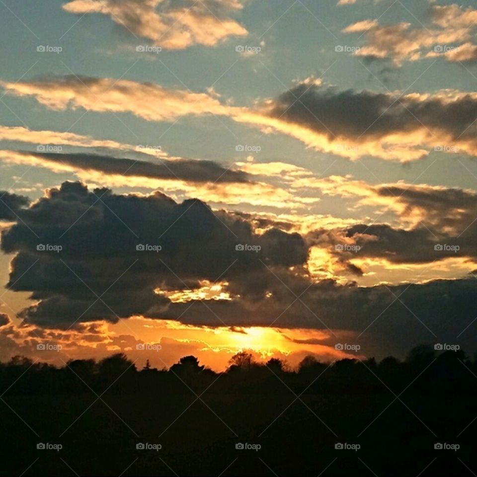 Cloud formation and sunset behind the trees.