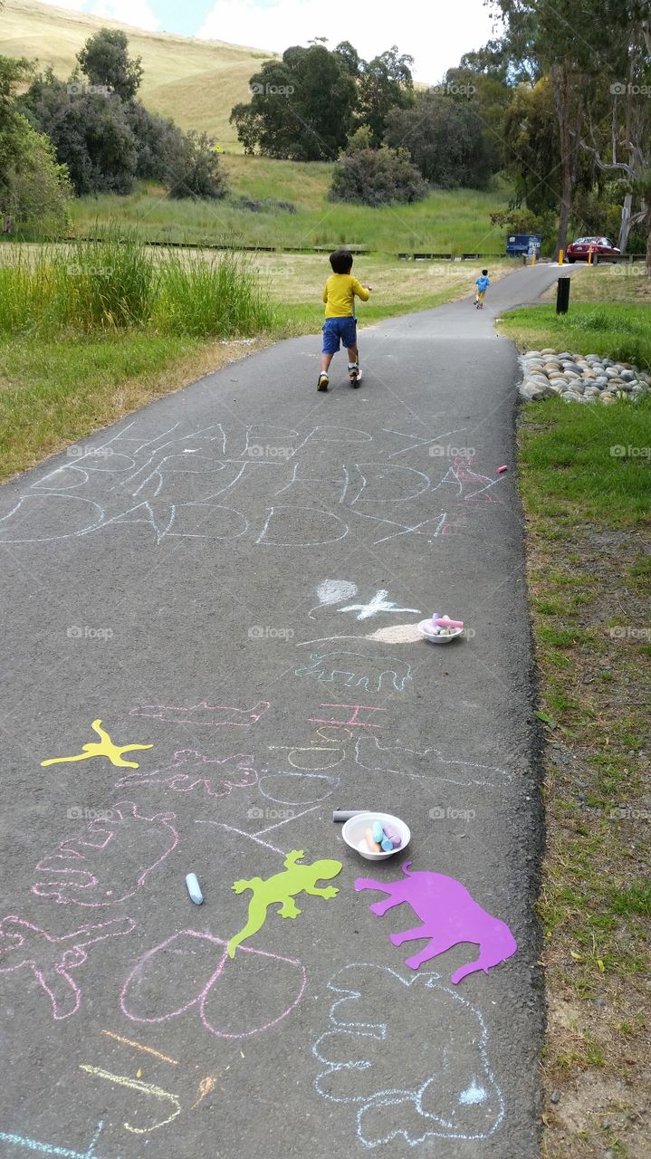 Kids playtime, riding scooter outside after doing chalk art