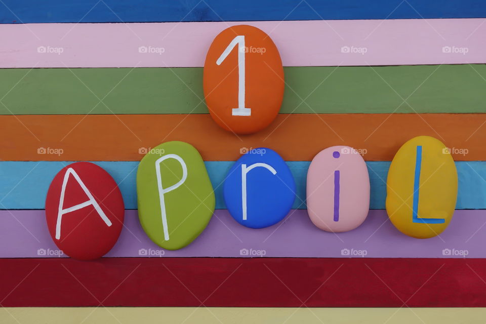 1 April, fool day scomposed with colored stones over a multi colored wooden board