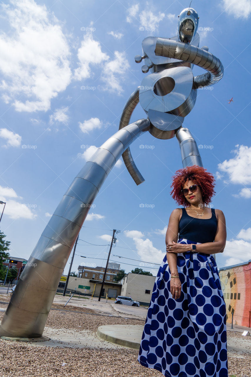 Woman standing in front of metallic sculpture