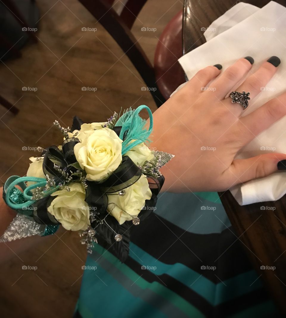 A prom corsage with white roses, black ribbon, and blue accents. 