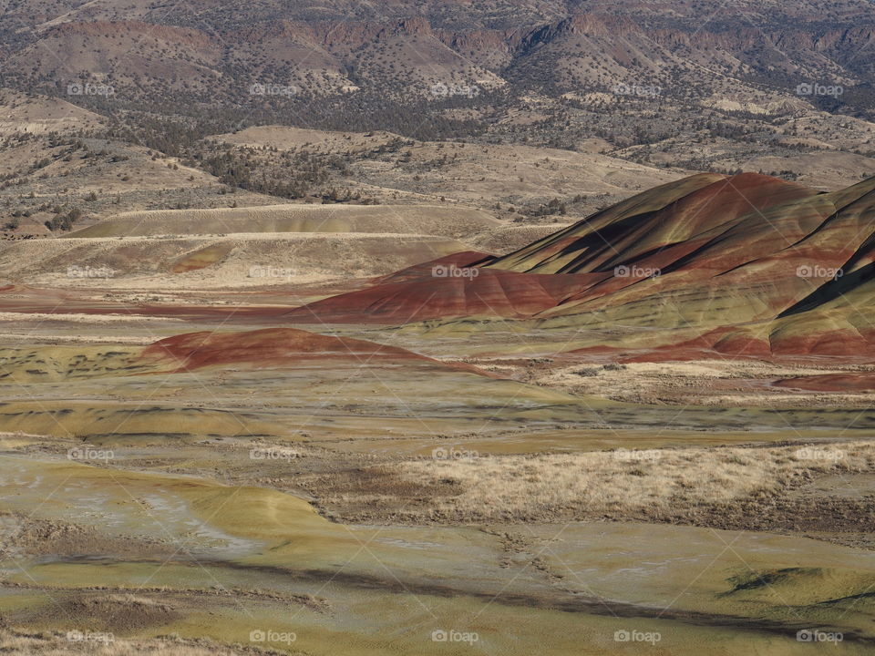 The incredible beauty of the red, gold, and browns of the textured Painted Hills in Eastern Oregon on a bright sunny day.