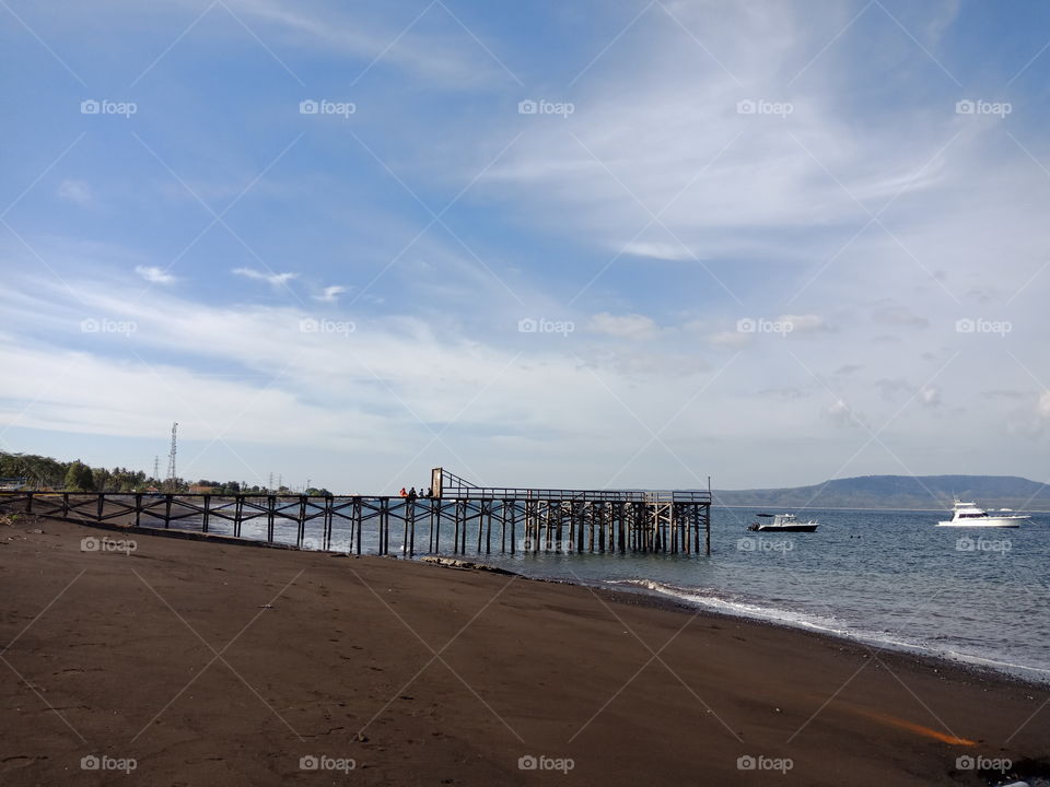 black sand beach with the bridge and boat