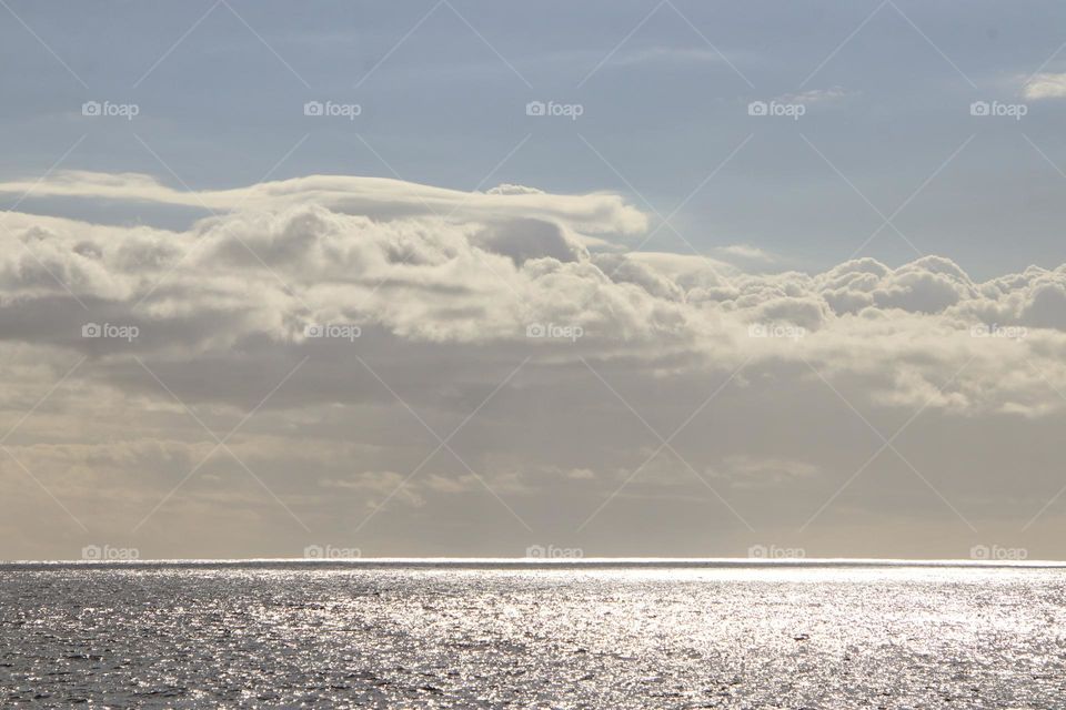The glistening in the atlantic ocean in the evening under cloudy sky
