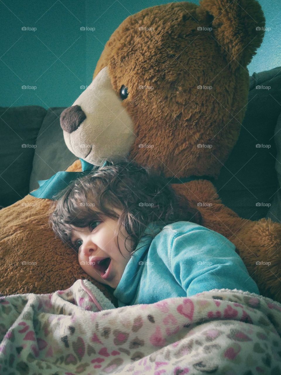 Small girl lying on bed with teddy bear