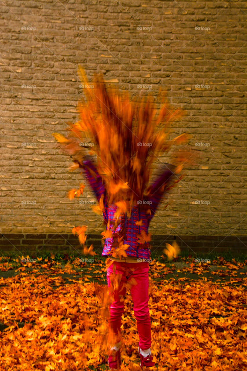 Little girl is trouwring Leafs up in the air