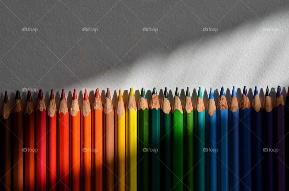 Colorful pencils and ray of light. White background.