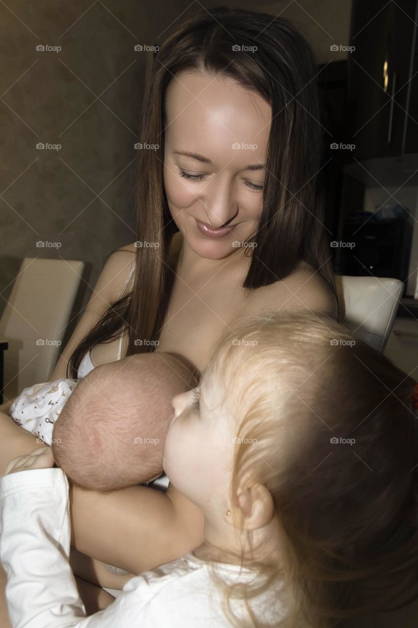A young, happy mother is breastfeeding her newborn baby.