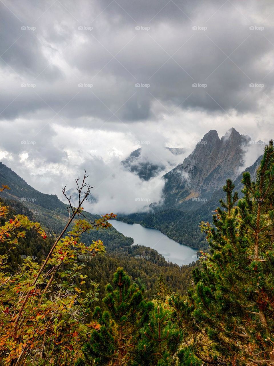 A lake in the valley of Pyrenees mountains in Catalunya, Spain. Clouds hover over the lake, creating a dark vibe