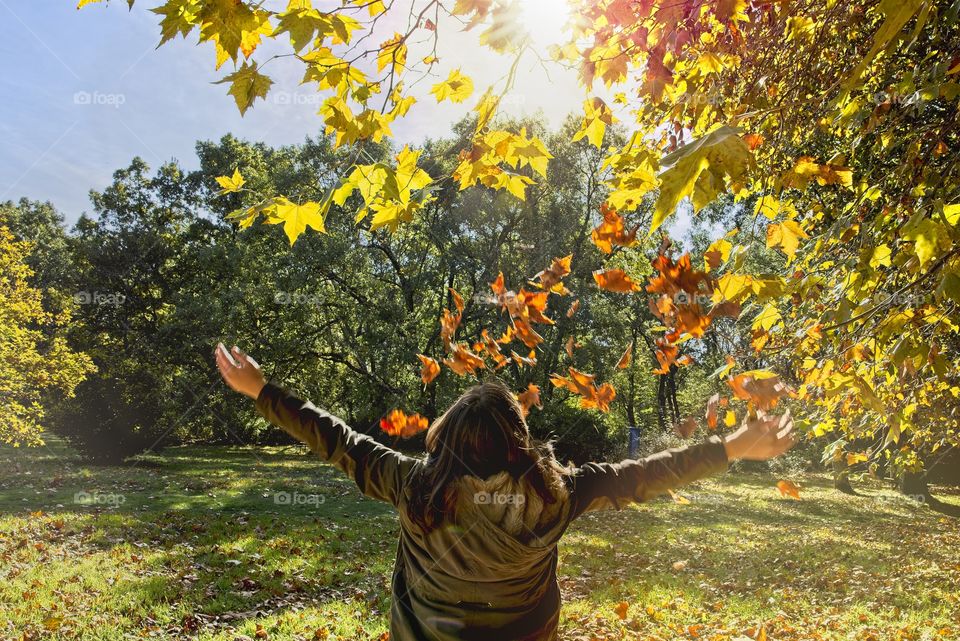 A girl enjoys the leaves falling in autumn