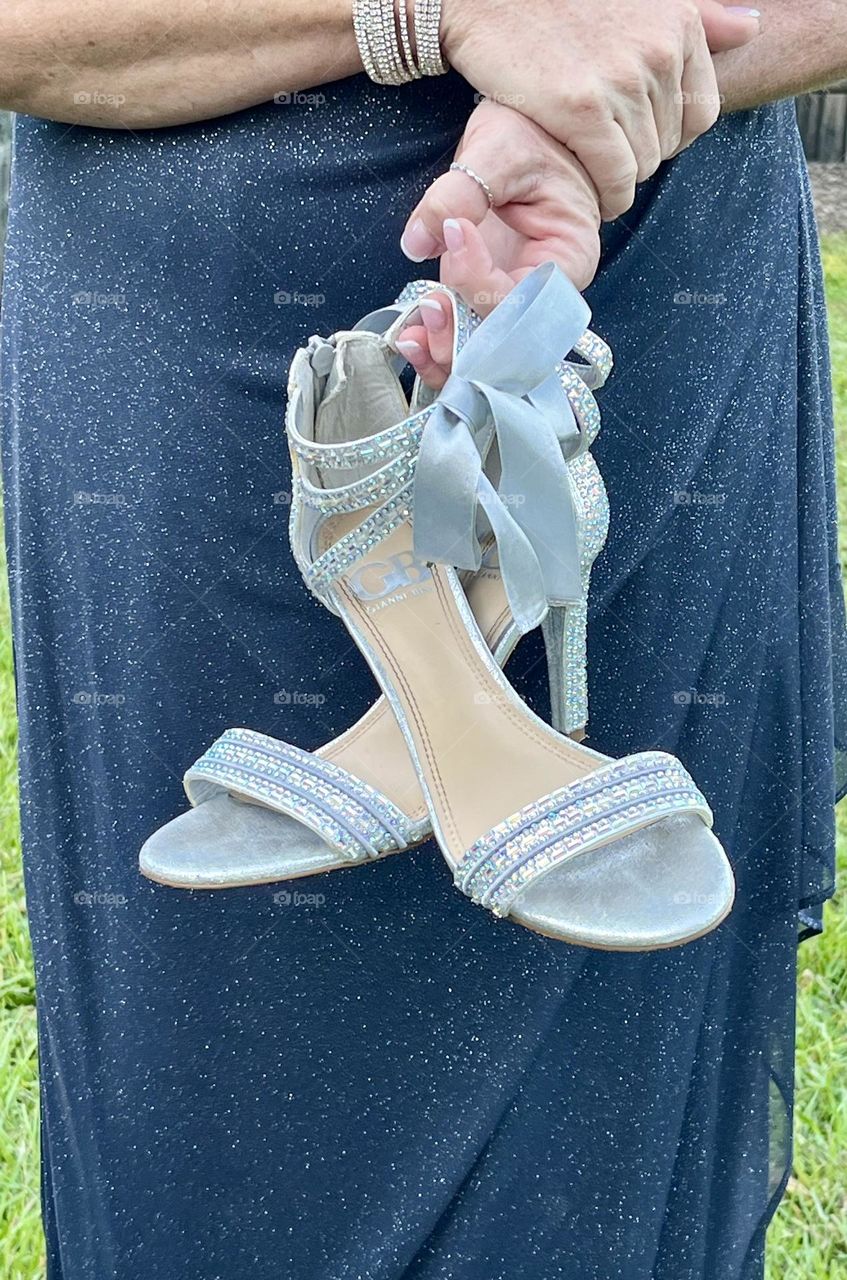 Pretty, sexy high heel Women’s shoes with bows held by hand in front of dress