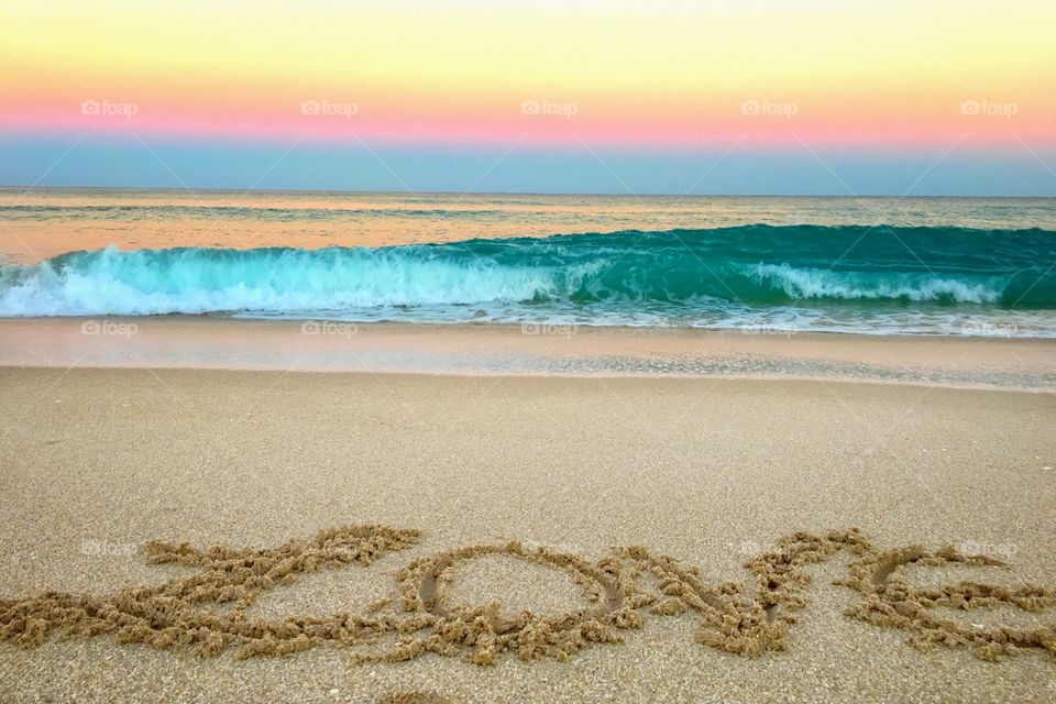 Love text on sand and waves