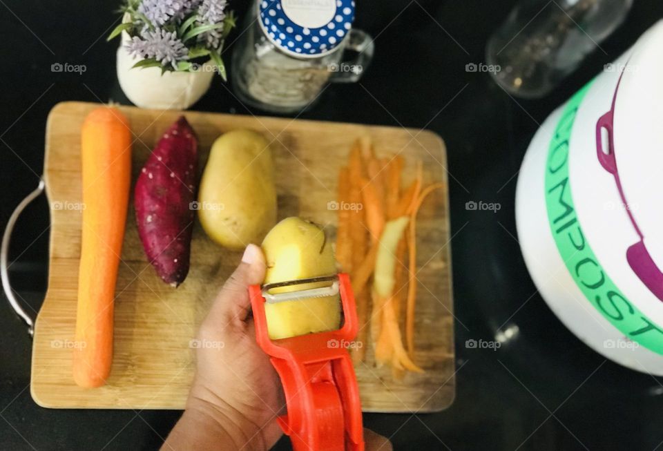 Daily collection of vegetable waste and make them into compost Leeds good environmental changes and it helps nature.here some root vegetables peeling with peeler and there is a compost box near to it.