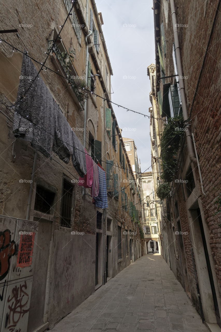 Drying laundry on an alley. Drying colorful laundry on a Venice, Italy alley corridor by old houses on a sunny day.
