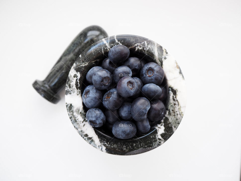 Beautiful blueberries in a mortar with a pestle.