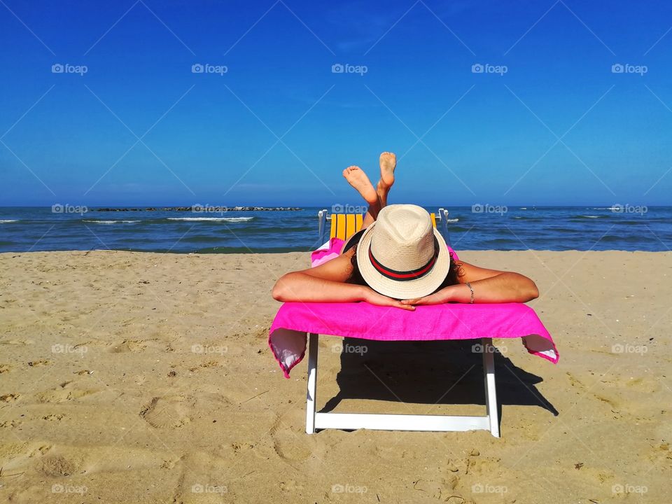 Woman with hat sunbathing at the sea