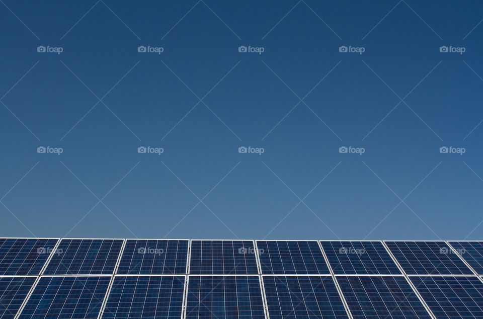 A row of solar panels generating clean electricity under a clear blue sky.
