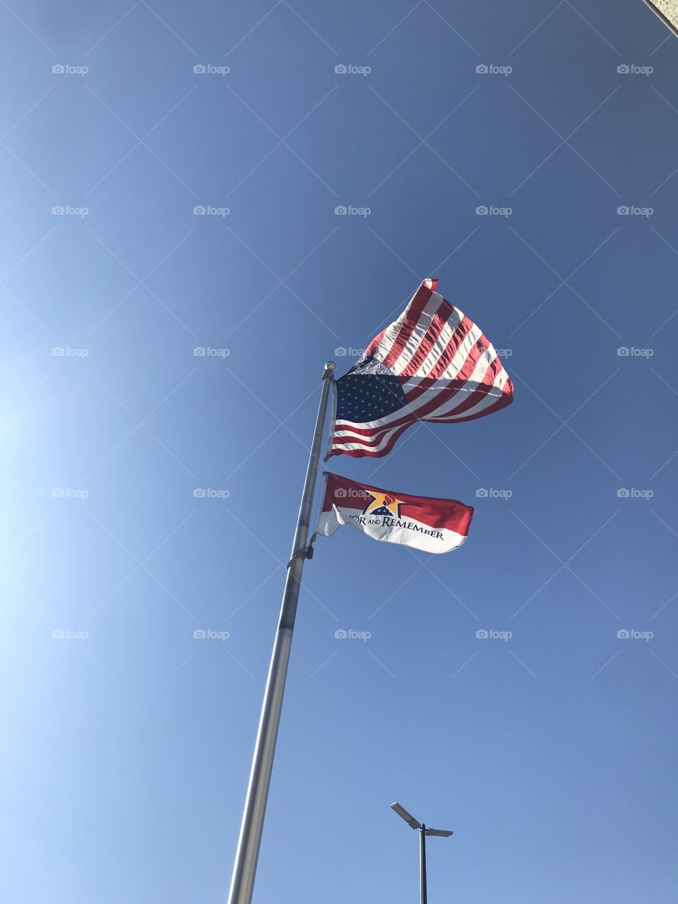 American flag & veteran flag flying with blue sky background on 9/11