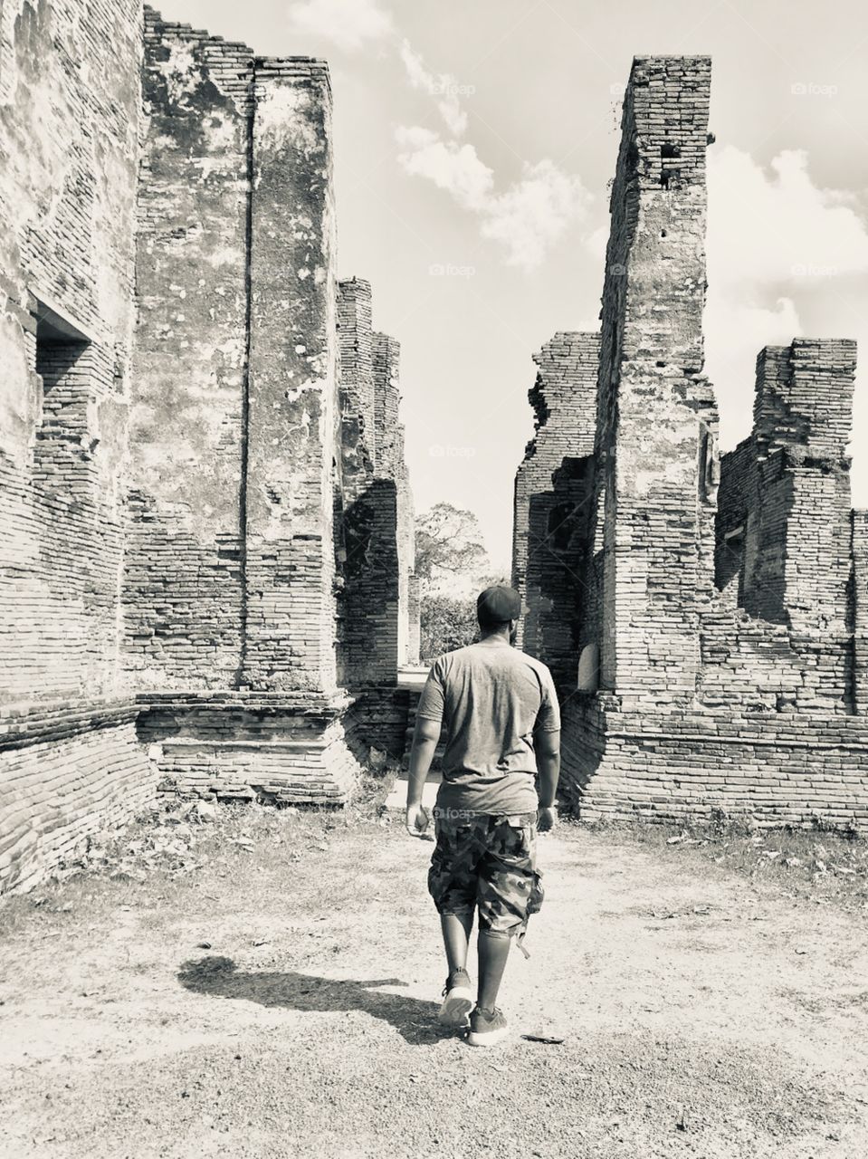 Man walking through what is left of the temple ruins in Ayutthaya Thailand 