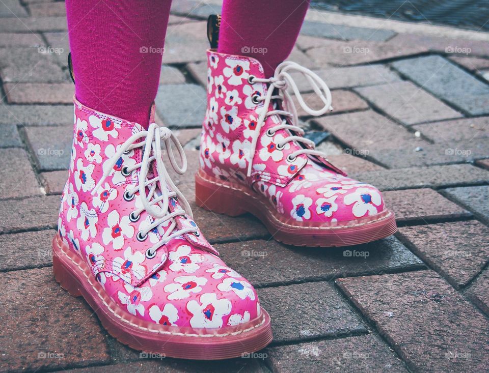 A pair of feet in pink, floral, lace up boots with shocking pink tights 