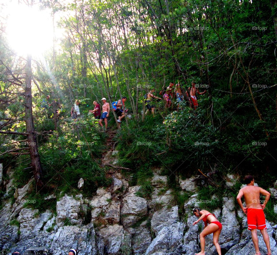 Group of Young Backpackers climbing in the bush to reach the waterfall in Italy, Friuli Venezia Giulia region.