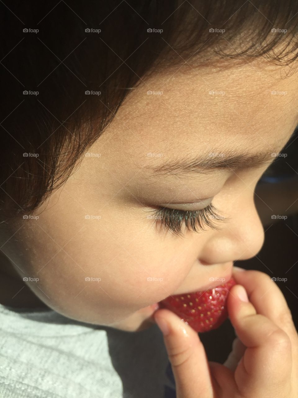 Little girl eating fresh strawberry